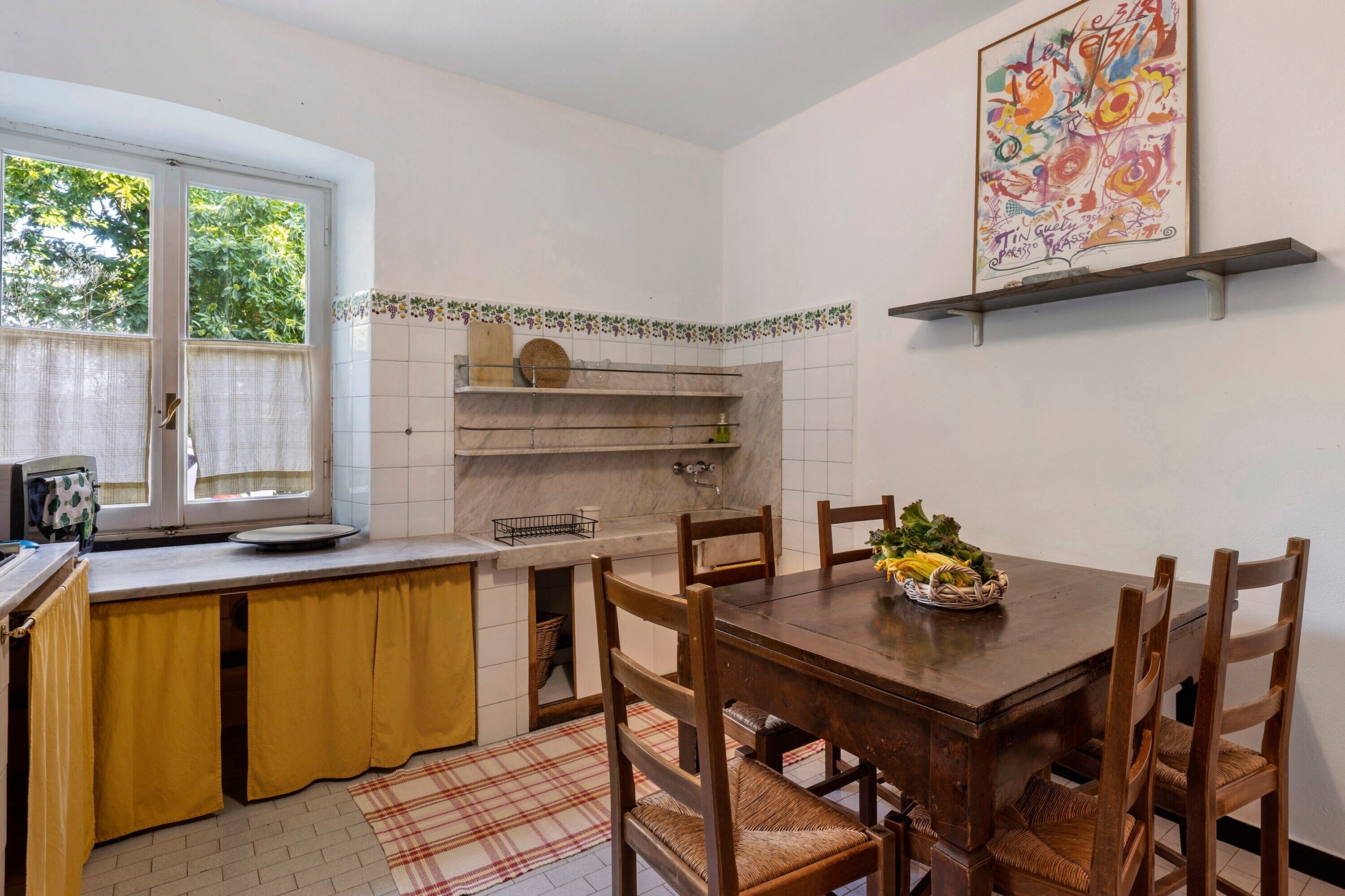 Una cocina con una mesa de comedor, sillas, un ventanal y un salpicadero de azulejos.