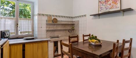 Una cocina con una mesa de comedor, sillas, un ventanal y un salpicadero de azulejos.