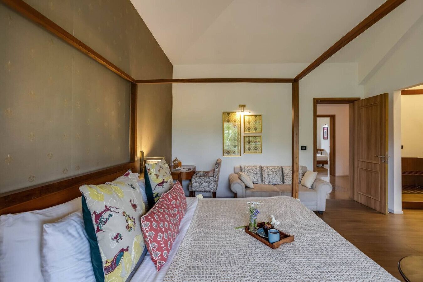 A spacious bedroom with a large bed, a sofa, and a wooden floor.