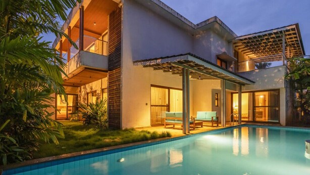 A modern house with a swimming pool, a covered patio, and a lush garden.