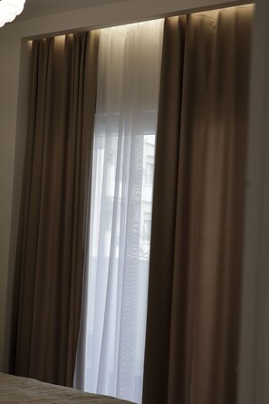 Una habitación con un ventanal, cortinas y una cama.