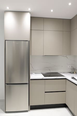 Una cocina moderna con refrigerador de acero inoxidable, salpicadero de mármol y muebles de cocina minimalistas.