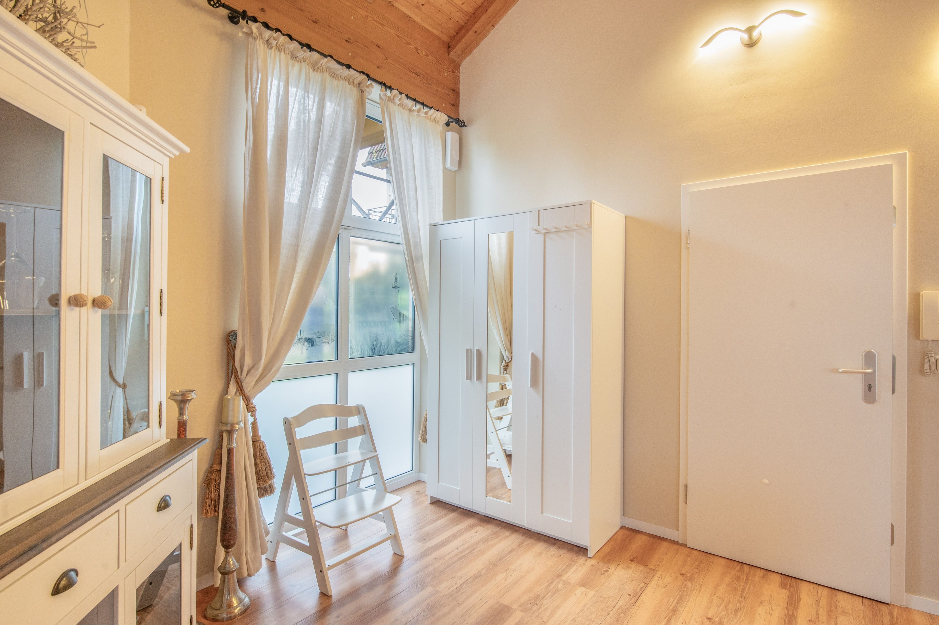 A room with a wooden floor, white wardrobe, and a chair.