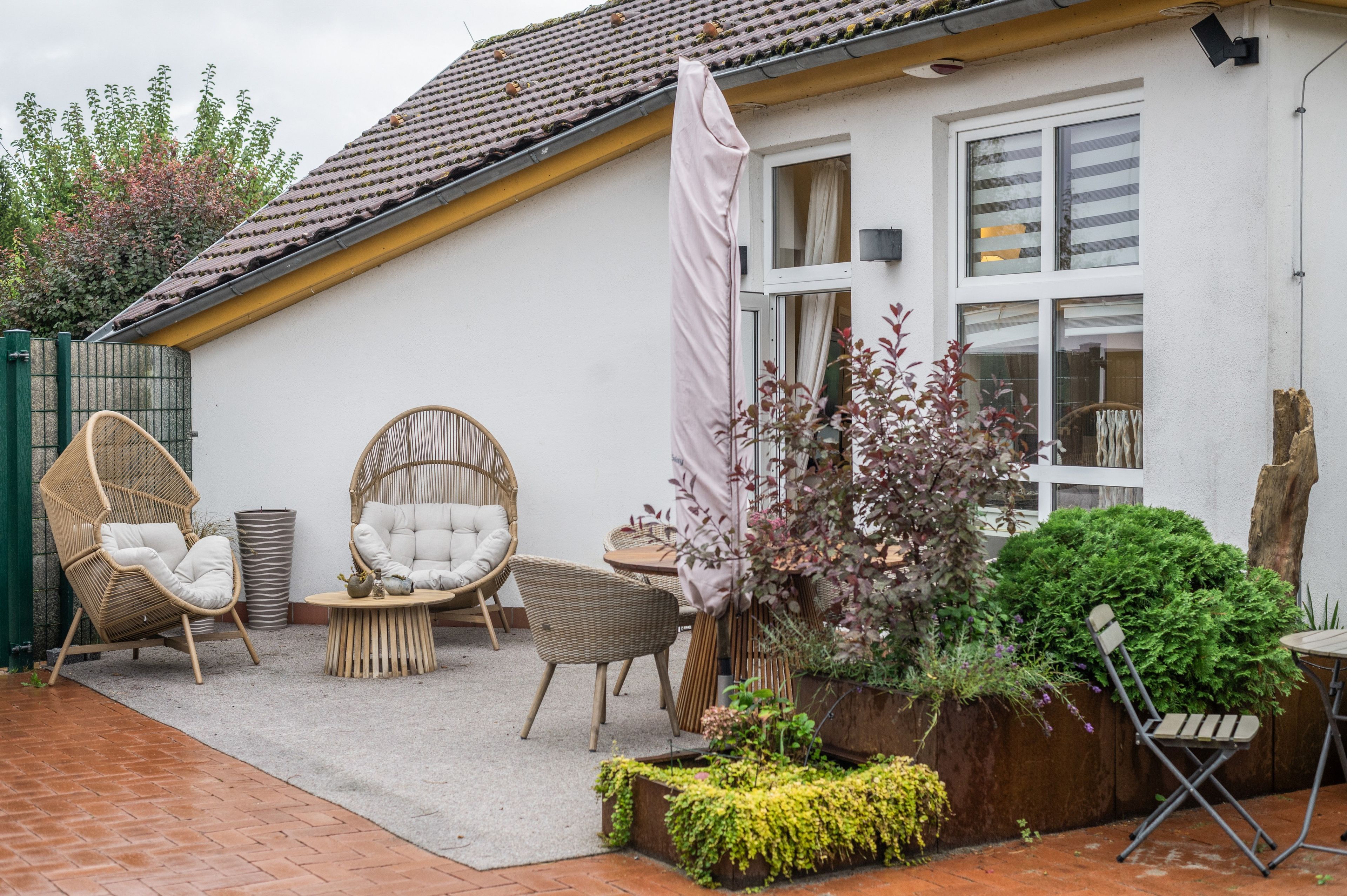Eine Terrasse mit Korbmöbeln, einem kleinen Tisch und einem Blumentopf.