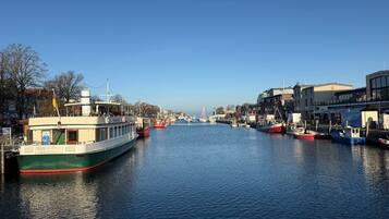 A calm river with boats docked along the banks, surrounded by buildings and trees.