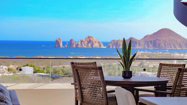 A balcony with wicker chairs, a table, and a potted plant. - Private Rooftop Terrace, Ocean Views & Pool Access (Cabo San Lucas)