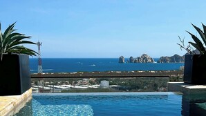 A clear blue pool with a view of the sea and rocky formations. - Private Rooftop Terrace, Ocean Views & Pool Access (Cabo San Lucas)