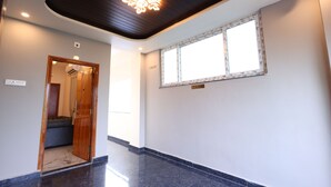 A hallway with a wooden door, a window with a view, and a ceiling with a light fixture. - Jonna Grand (Tirupati)