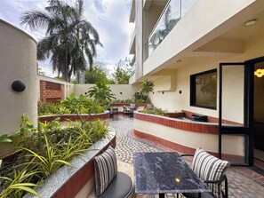 A modern outdoor patio with seating, a table, and a variety of plants. - The Four Stories - Luxury Near The Lake (Udaipur)