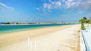 Een strand met heldere lucht, een zandstrand en een uitzicht op een stadsbeeld in de verte.