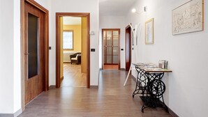 Un couloir avec des portes en bois, une table recouverte de papiers et un croquis encadré accroché au mur.