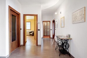 A hallway with wooden doors, a table with papers, and a framed sketch on the wall.