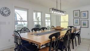 Un comedor con una mesa de madera, sillas negras, una araña y un reloj en la pared.