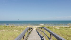 Un paseo marítimo de madera que conduce a la playa, con vista despejada al océano.