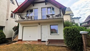 A two-story residential building with a balcony, a garage, and a small garden area.