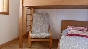 A bunk bed with a wooden ladder, a single bed with patterned bedding, and a chair with a patterned cushion. - 10m from ski slopes, 2nd floor, balcony, ski locker, 36m², Méribel-Mottaret (Méribel - Les Allues)