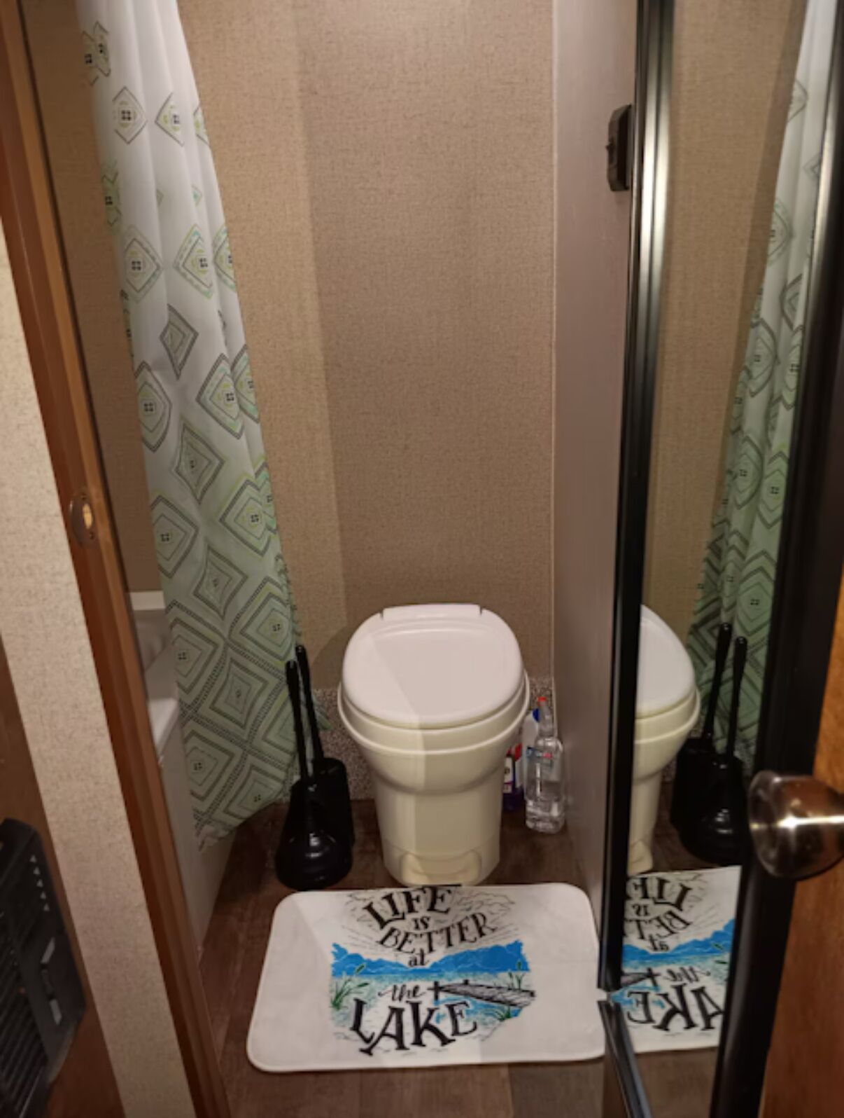 A small bathroom with a toilet, a bidet, and a mirror. There are two placemats on the floor with text.