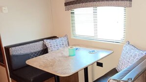 Un intérieur de camping-car compact comprenant un coin cuisine, une table à manger et des espaces salon.