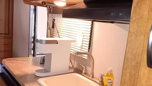 Une petite cuisine équipée d’un four à micro-ondes, d’un grille-pain, d’un évier et d’une cuisinière.
