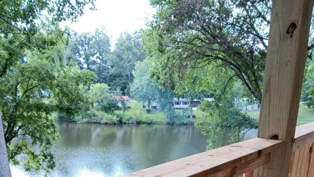 Une terrasse en bois offrant une vue sur un lac et la végétation environnante.