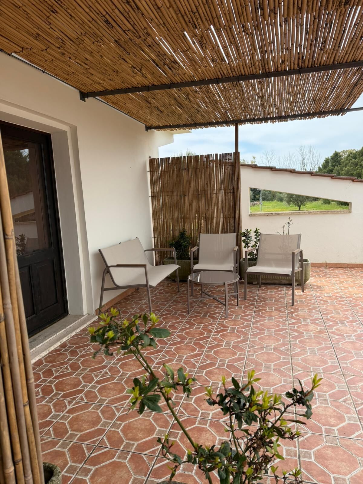 A patio with hexagonal tiles, a bamboo ceiling, and two chairs.