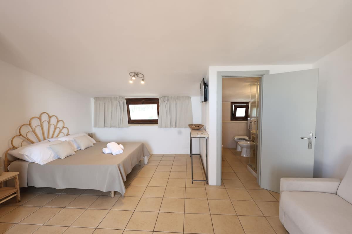 A bedroom with a bed, bedside table, and a view into the bathroom.