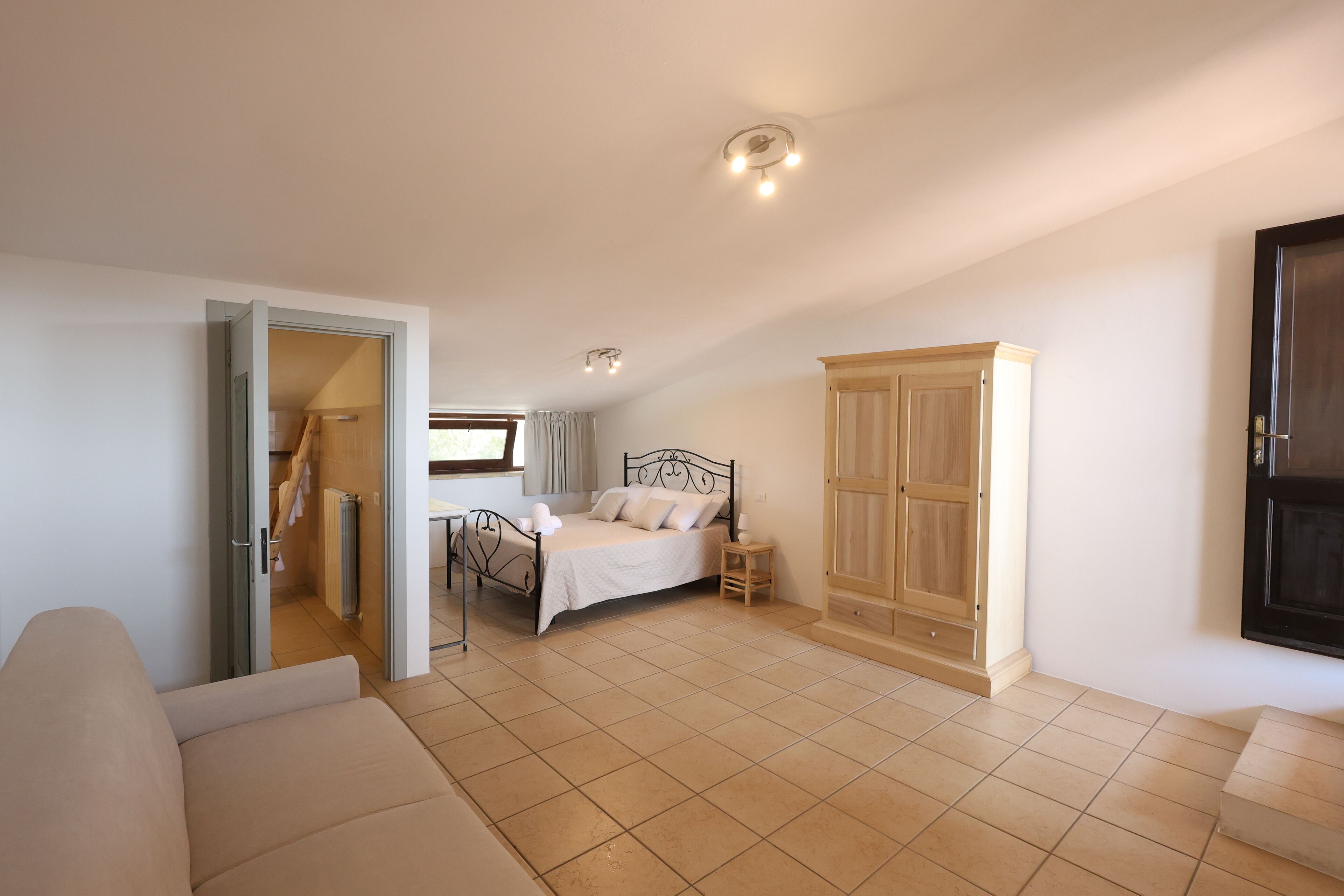 Une chambre à coucher comprenant un lit, une armoire, un radiateur et une porte donnant sur une autre pièce.