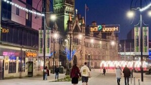 Un edificio histórico con una torre de reloj, iluminado por farolas y luces decorativas.