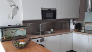 Et moderne køkken med hvide skabe, en mikrobølgeovn, en vask og en træbordplade.