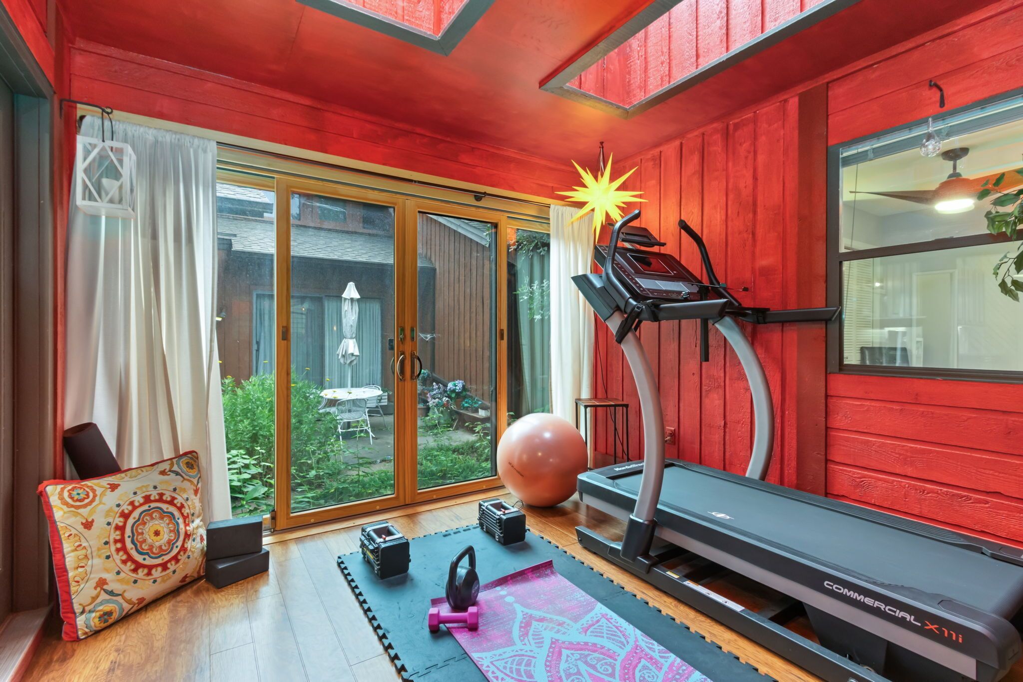 Een huisgym met een loopband, fitnessballen en gewichten.