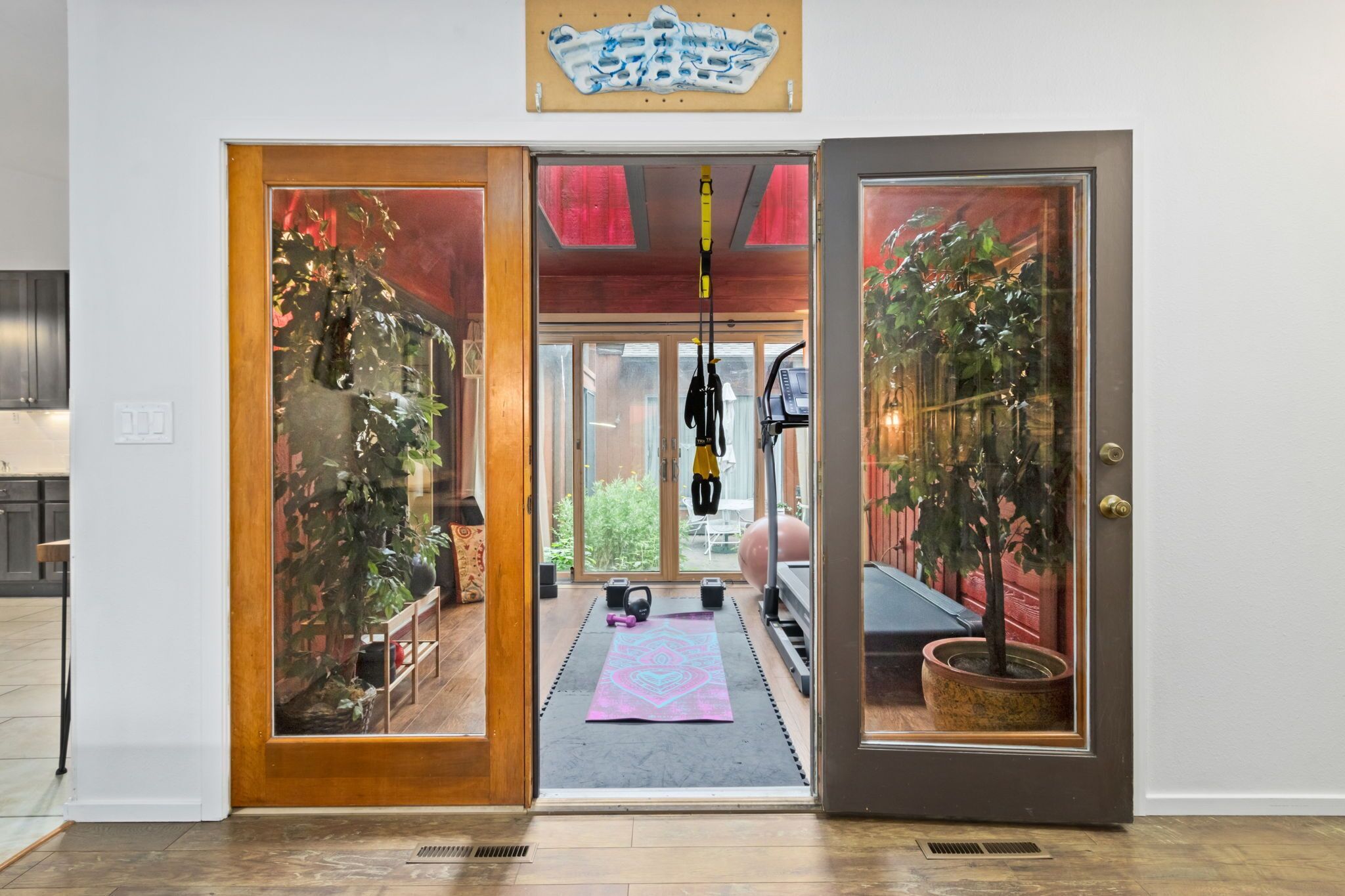 A doorway leading to a room with a yoga mat, exercise equipment, and a potted plant.