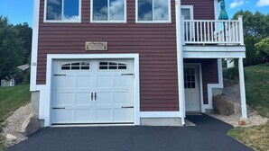 A two-story house with a garage, a balcony, and a sign that reads "The McElroy Lake House". - Fabulous 3-bedroom Weirs Beach Village home in Laconia. (Laconia)