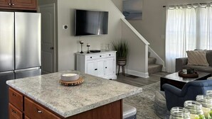 A modern kitchen with a granite countertop, wooden cabinets, and a stainless steel refrigerator. - Fabulous 3-bedroom Weirs Beach Village home in Laconia. (Laconia)