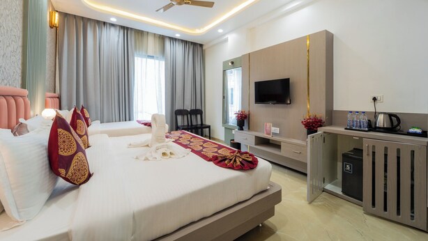 Una habitación de hotel moderna con una cama grande, un escritorio con televisor de pantalla plana, un ventilador de techo y un mini bar.