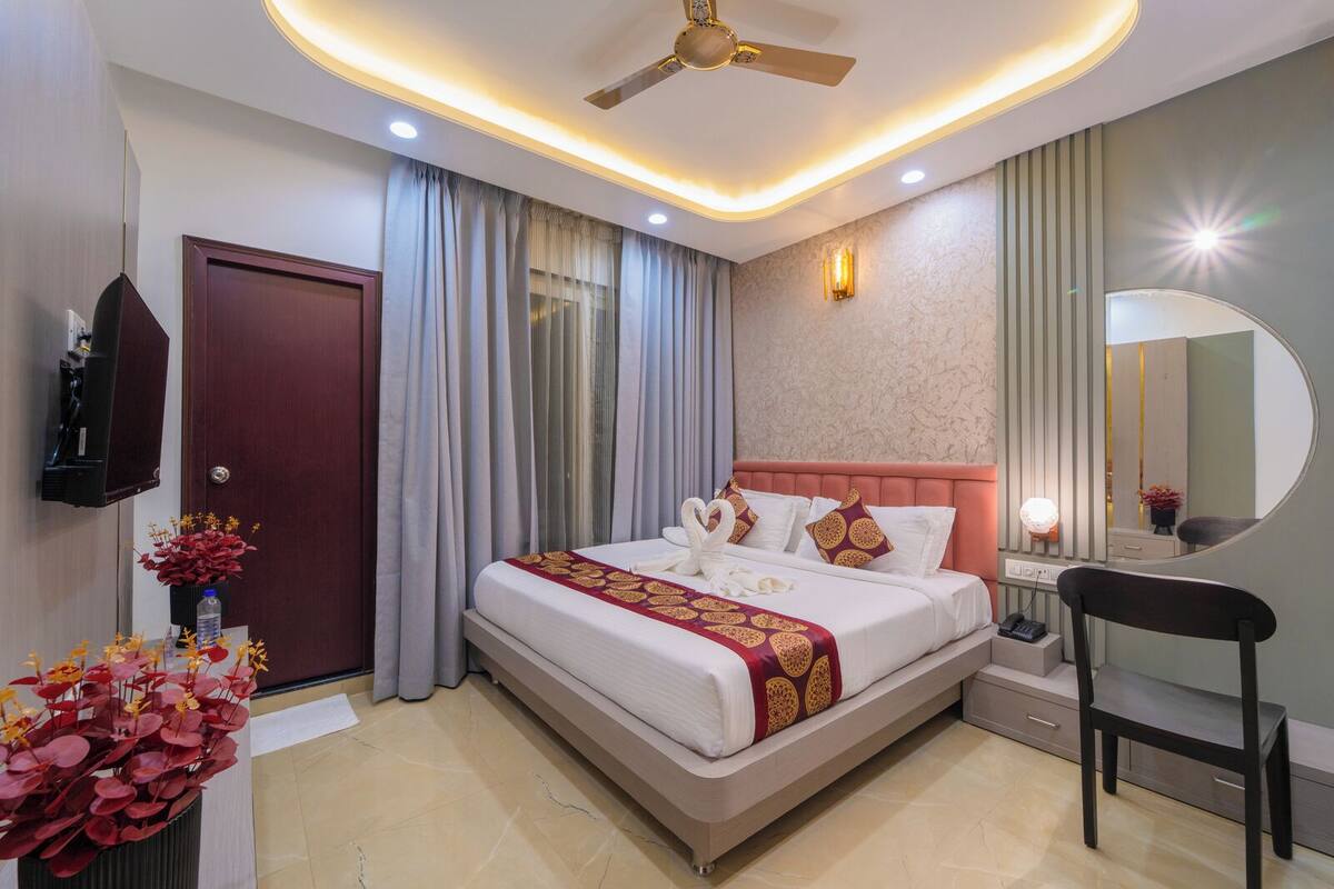 Une chambre d’hôtel moderne avec un grand lit, un ventilateur de plafond, une table de chevet, une chaise et un miroir.