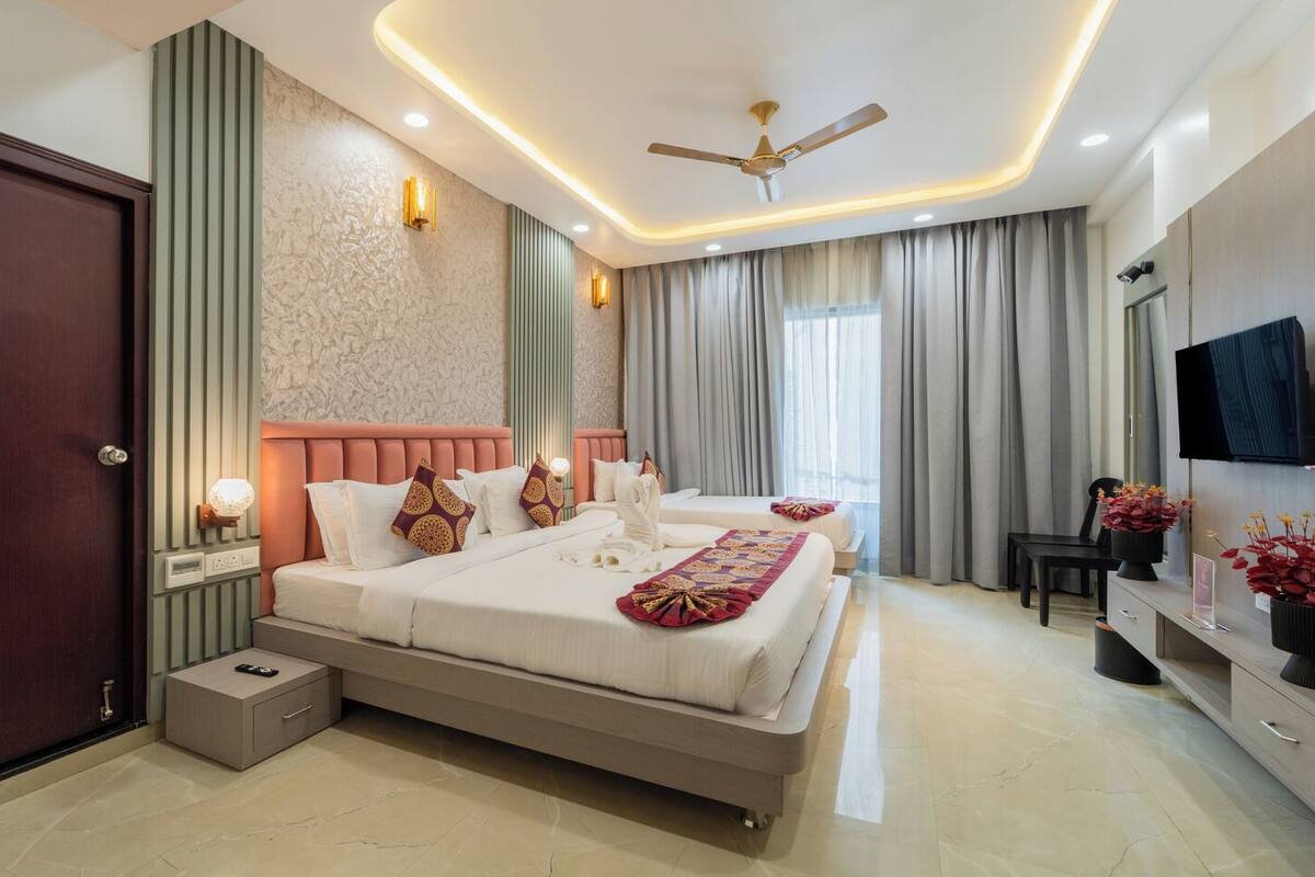 Une chambre d’hôtel moderne avec un grand lit, des tables de chevet, une télévision et un ventilateur de plafond.