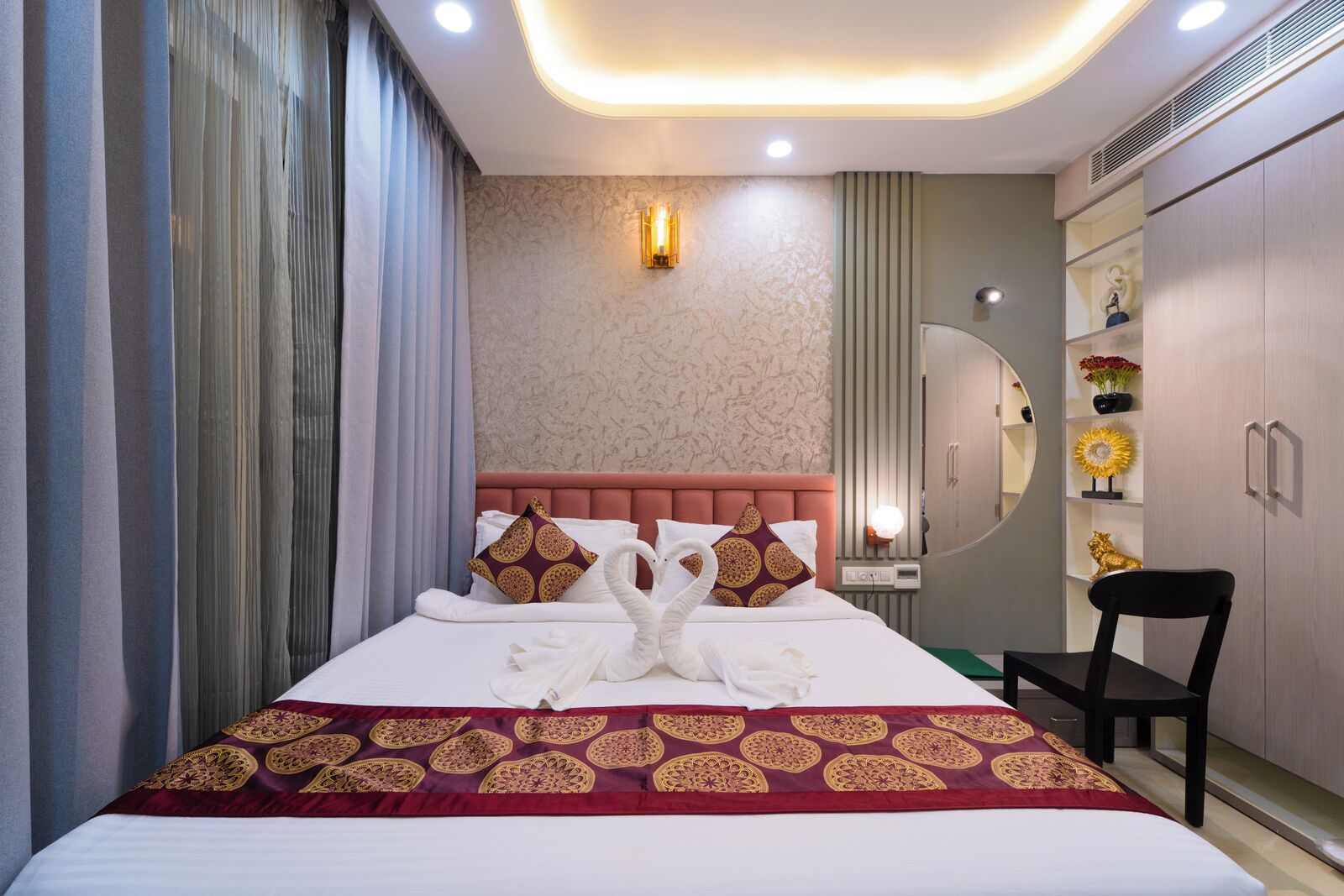 Una habitación de hotel con una cama grande, un tocador con espejo y un armario.