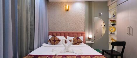 Una habitación de hotel con una cama grande, un tocador con espejo y un armario.