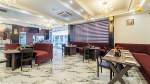 Un restaurante con pisos de mármol, asientos tapizados en rojo y candelabros.