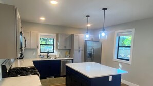 A modern kitchen with a central island, built-in appliances, and a view of the outdoors. - Lake Breeze Cottage 6 beds w AC, hot tub near Lake Michigan beach and The Deck. (Muskegon)