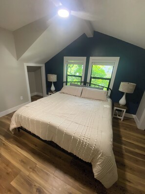 Quarto com uma cama grande, duas janelas e um ventilador de teto.