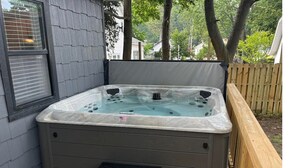 A hot tub on a wooden deck with a wooden fence and a house in the background. - Lake Breeze Cottage 6 beds w AC, hot tub near Lake Michigan beach and The Deck. (Muskegon)