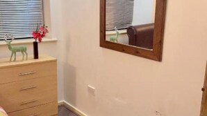 Ein Schlafzimmer mit einem Holzschrank, einem Spiegel und einem Fenster mit Jalousien.