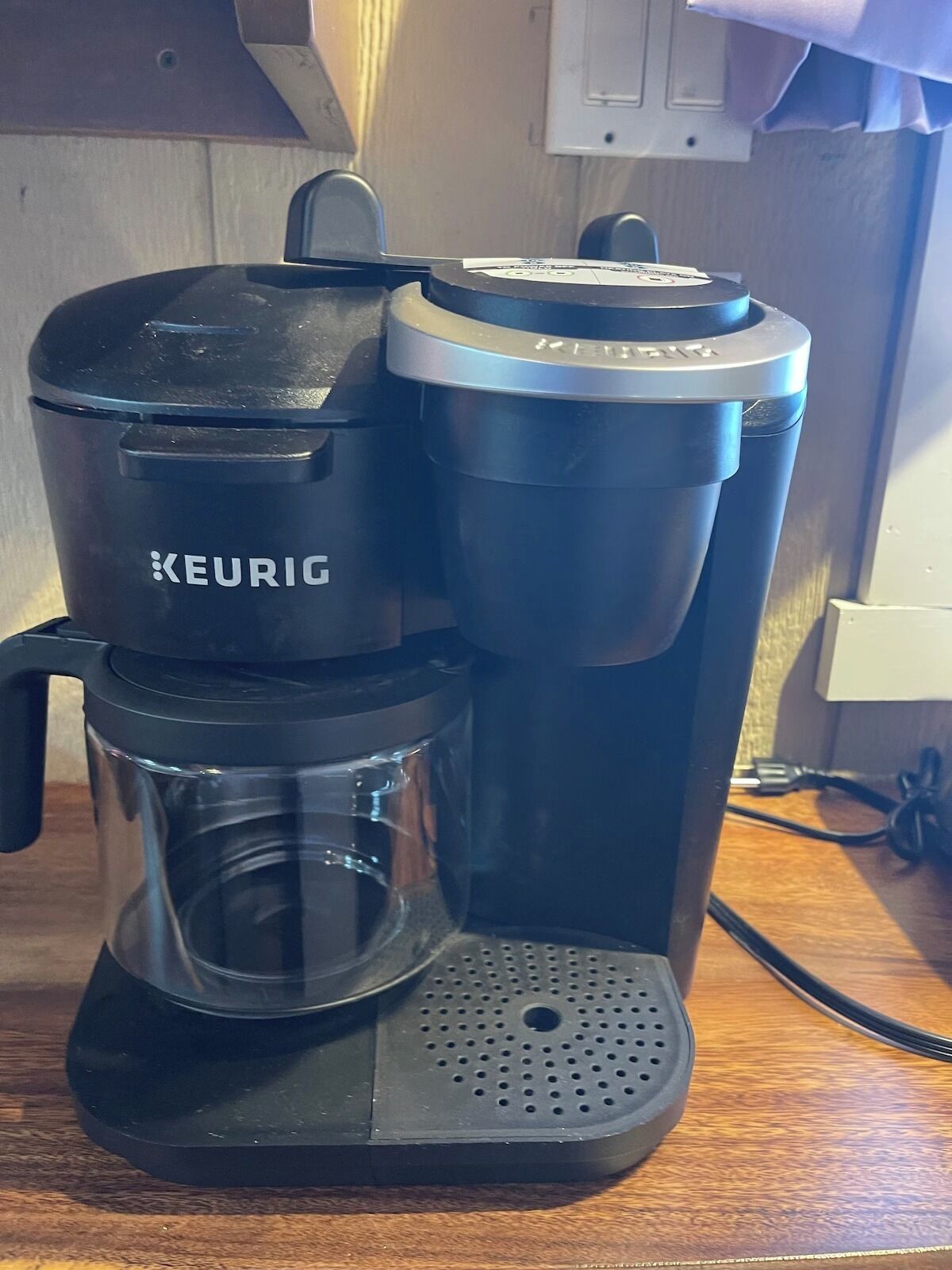 A Keurig coffee maker with a glass carafe and a drip coffee pot on a wooden countertop.