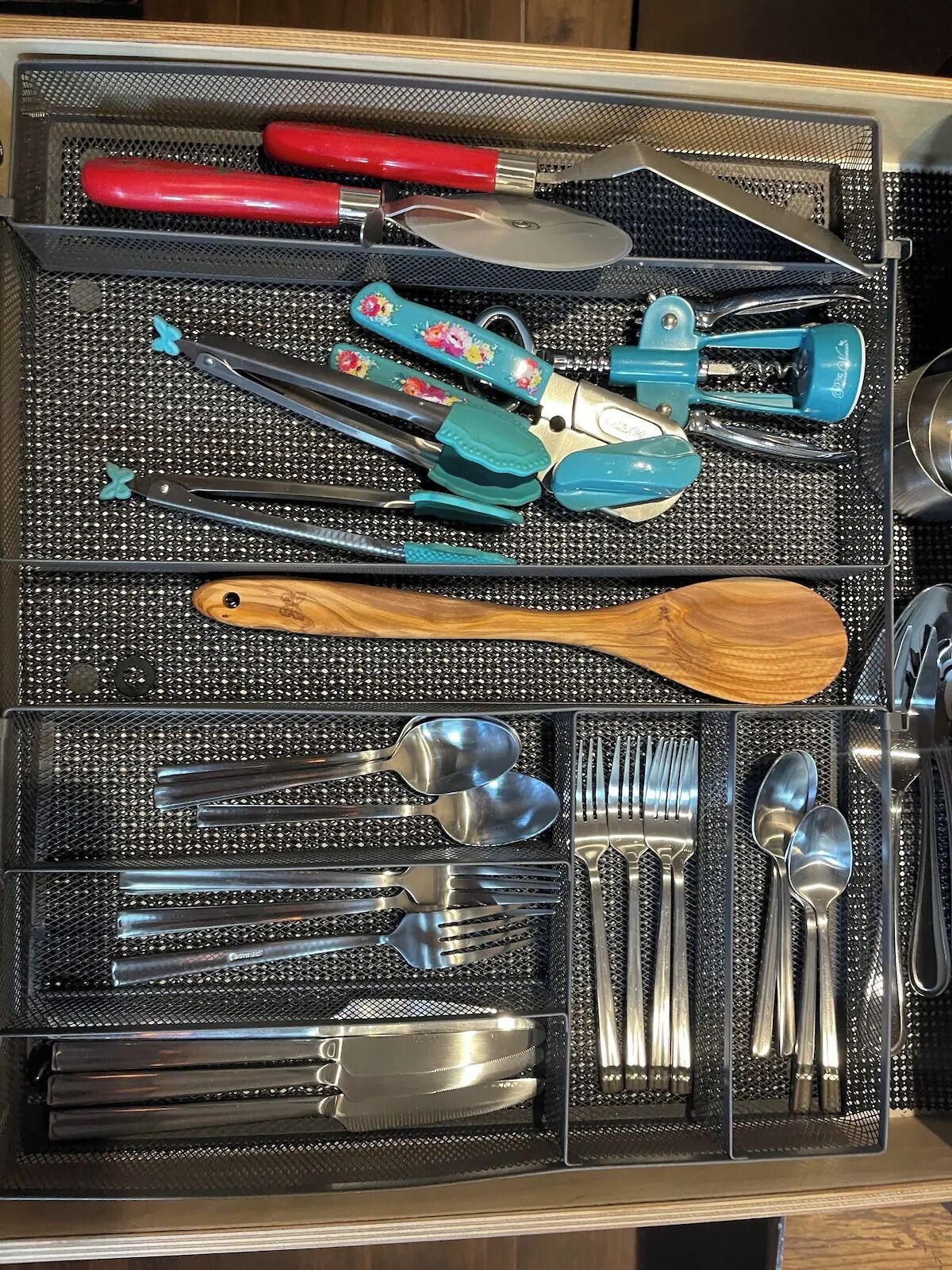 Een lade gevuld met verschillende keukengereedschappen, zoals een tang, spatel en rasp.