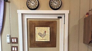 Una puerta con un panel decorativo que muestra un diseño de gallo, dos relojes de pared encima, y una puerta corredera con un diseño triangular.