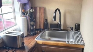 Una cocina compacta con encimera de madera, un lavamanos integrado, un tostador y un oso decorativo en la pared.