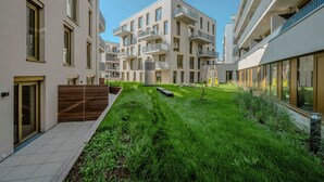 Un edificio de apartamentos moderno con varios balcones, un patio cuidado y un diseño limpio y contemporáneo.
