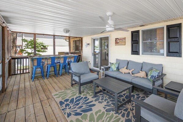 A covered outdoor seating area with a sofa, chairs, and a table.