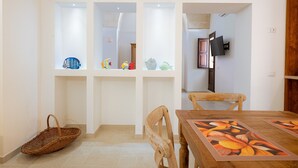 Een eethoek met een houten tafel, stoelen en een decoratieve tafelkleed.